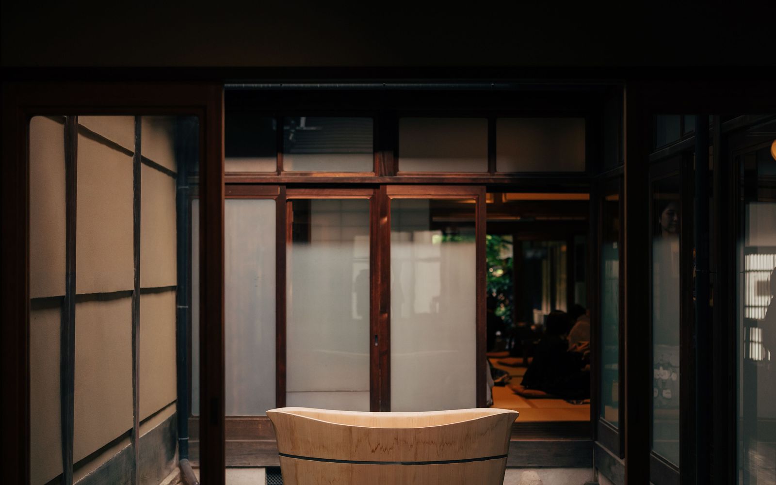 A wooden hinoki bathtub standing on moss in the courtyard of a traditional Japanese house