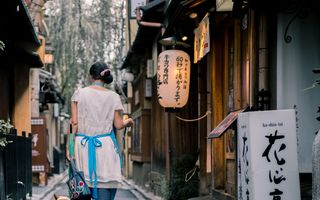 A narrow lantern-lit lane of wooden buildings in Kyoto at dusk