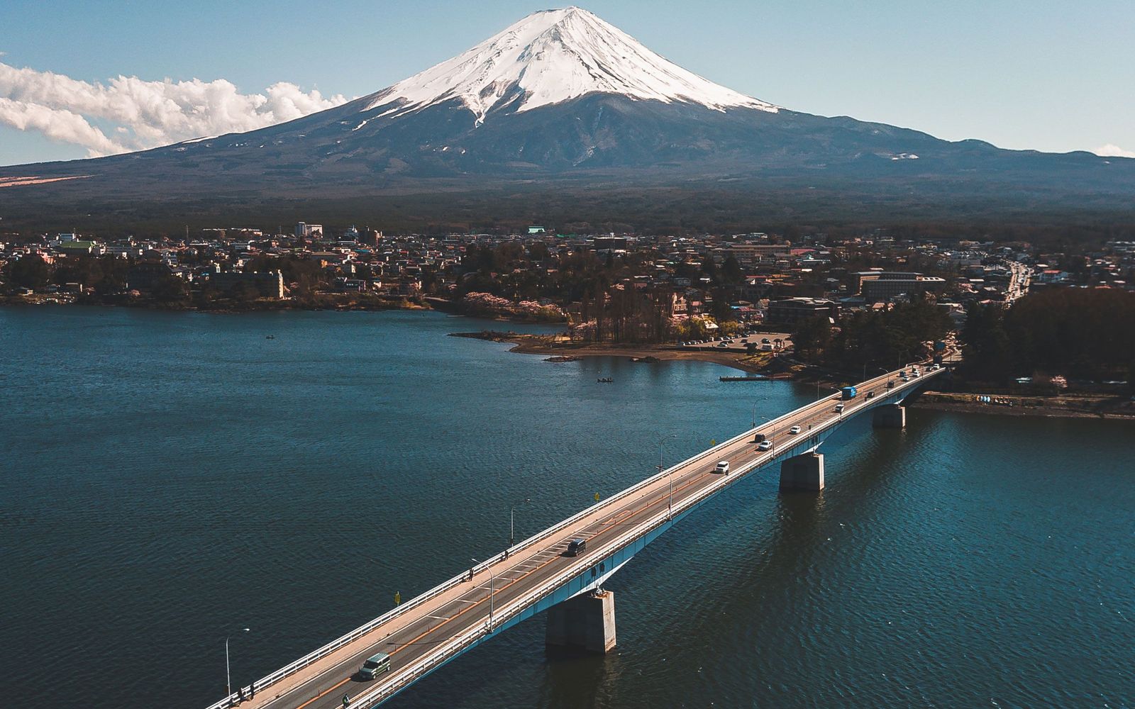 Mount Fuji rising beyond a lake and a long road bridge in the Fuji Five Lakes