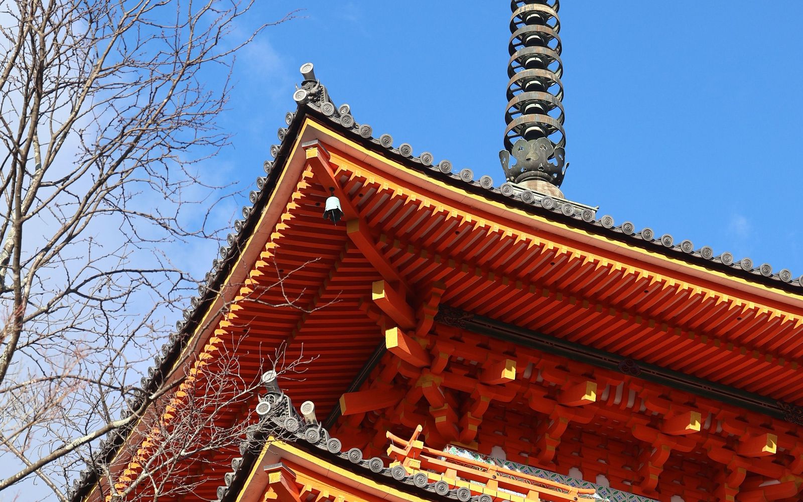 The vermilion eaves and finial of a Japanese pagoda against a clear sky